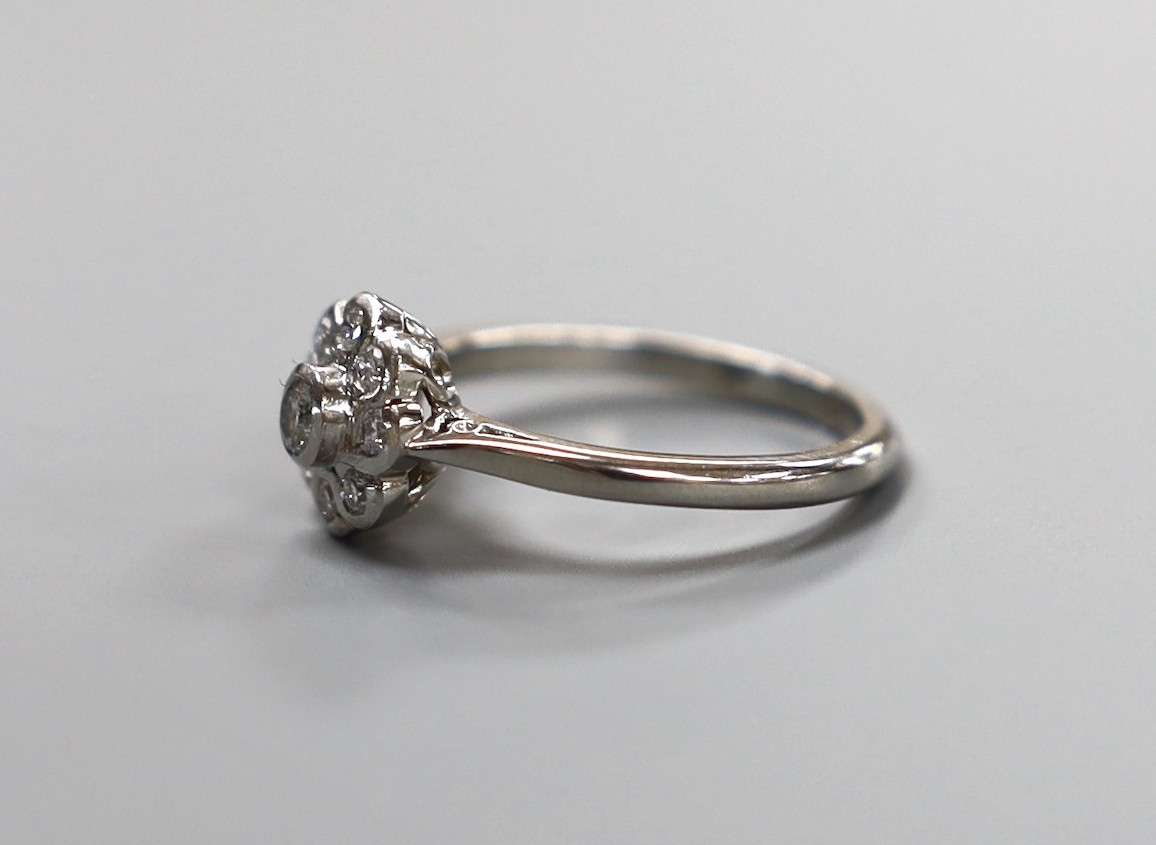 A modern platinum and collet set nine stone diamond flower head cluster ring, size O, gross weight 5.6 grams